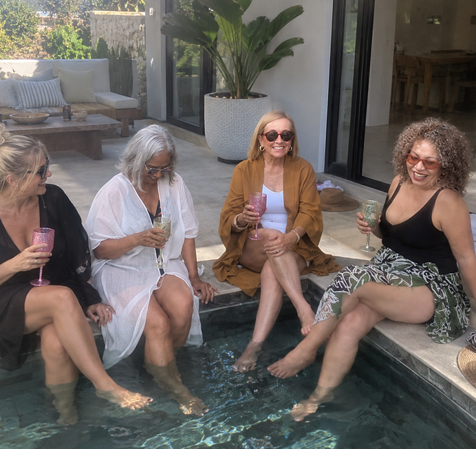 Four women laughing with their feet in a plunge pool
