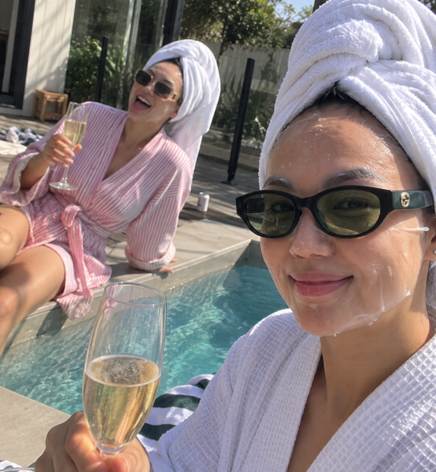 Jessica and a friend in robes and face masks by a pool
