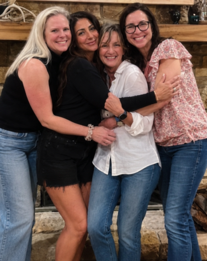 Four women with their arms around each other, laughing.