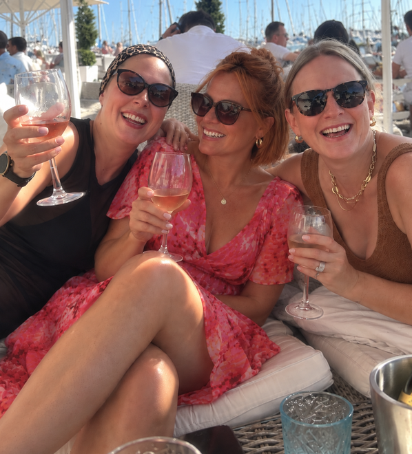 Kelly and her friends laughing at a marina bar in the sunshine