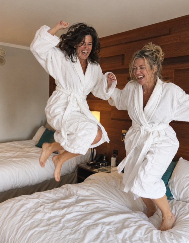 Sharon and a friend jumping on hotel beds in robes