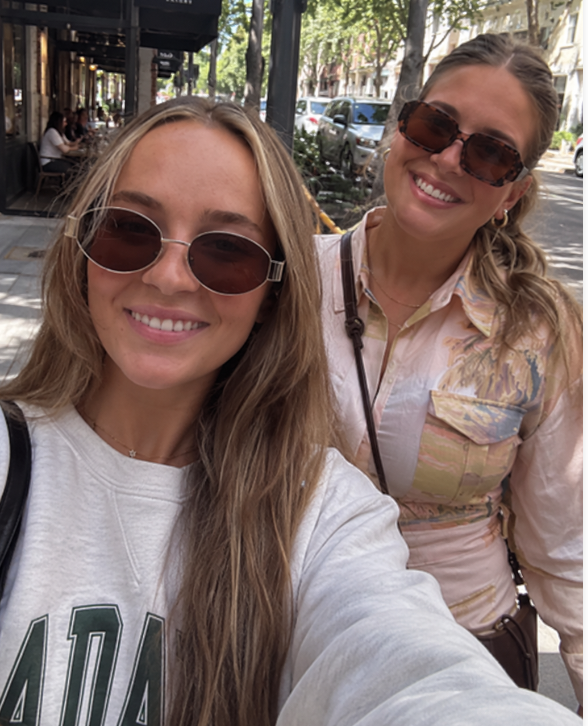 Two women taking a selfie on a tree lined city street