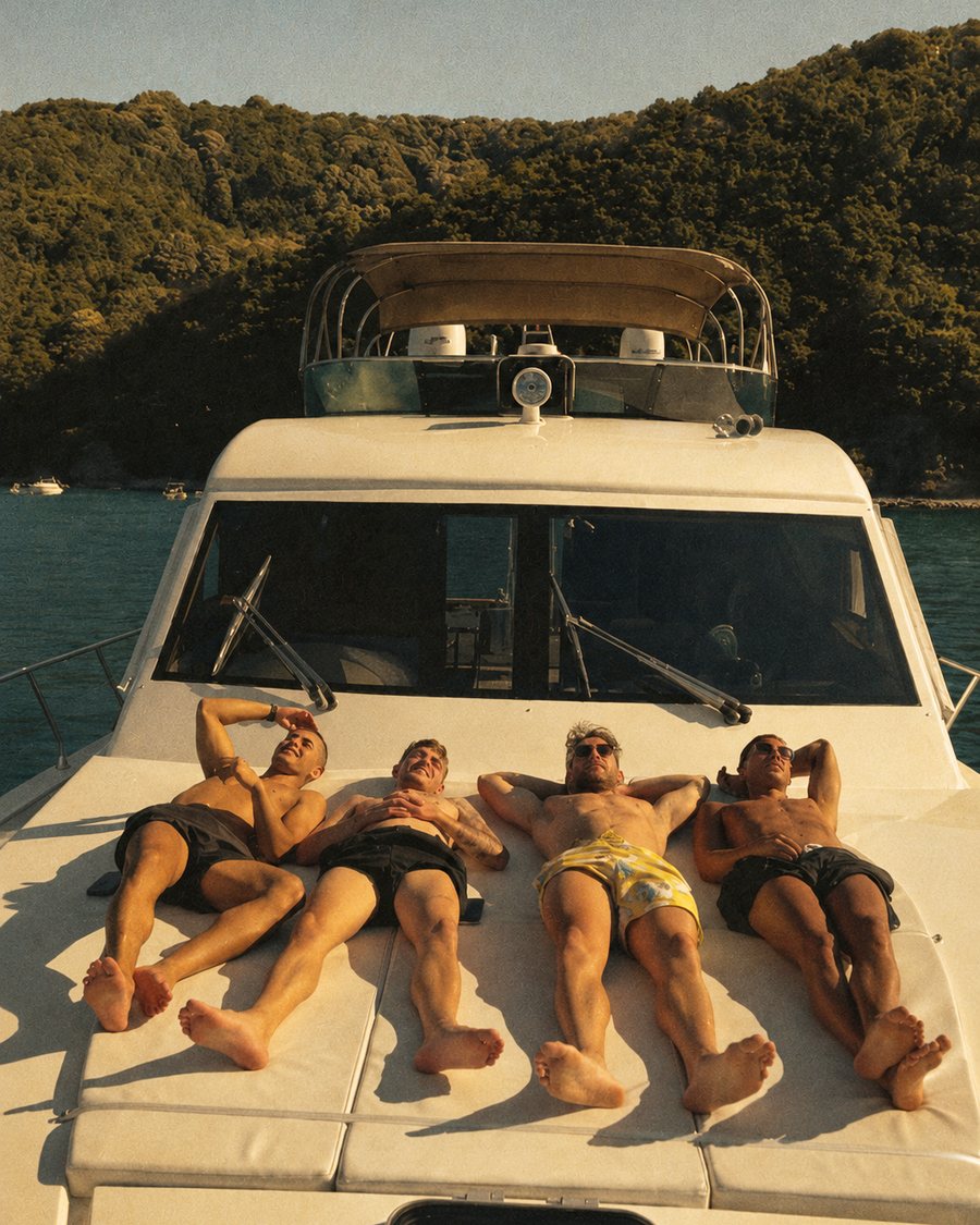 Four mates sunbathing on the bow of a boat