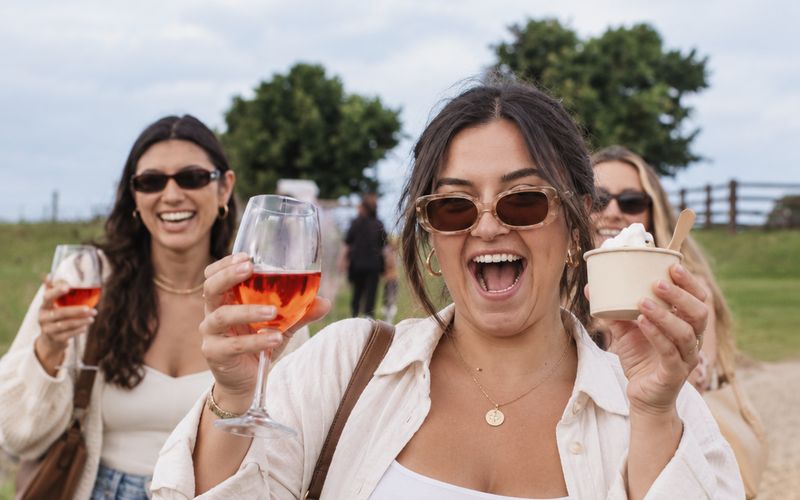 Friends laughing with glasses of rosé on a sunny winery walk