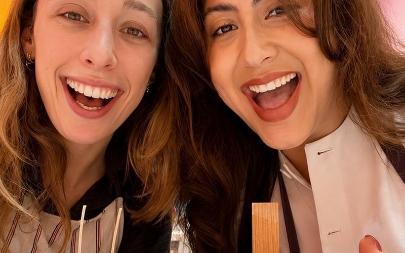 Two friends grinning in a selfie with the candles they just made on a Sydney girls weekend