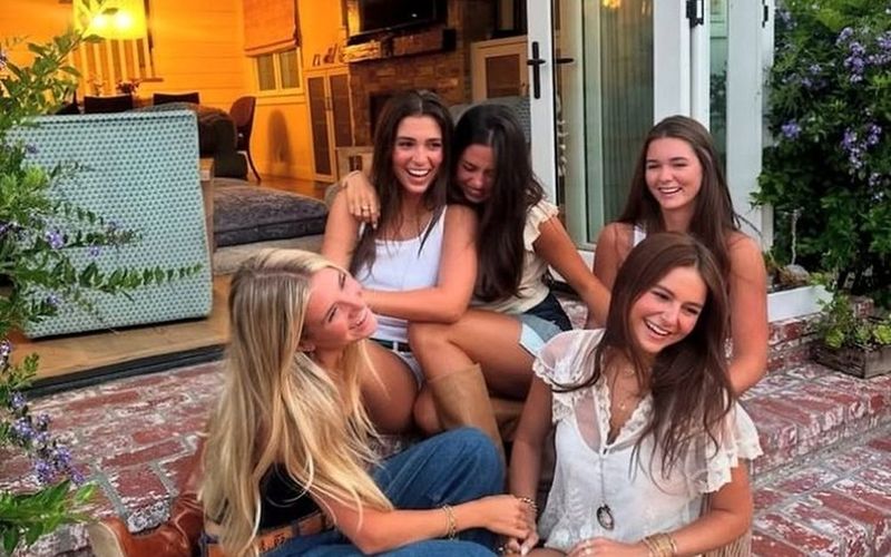 Four friends laughing together on the steps of the apartment on a Sydney girls weekend