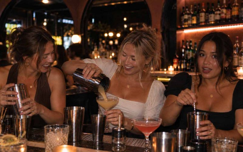 Friends shaking and pouring their own cocktails at a cocktail class on a Sydney girls weekend