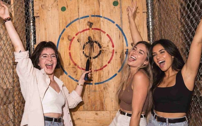 Three friends celebrating a bullseye together during a girls trip axe throwing session in Melbourne