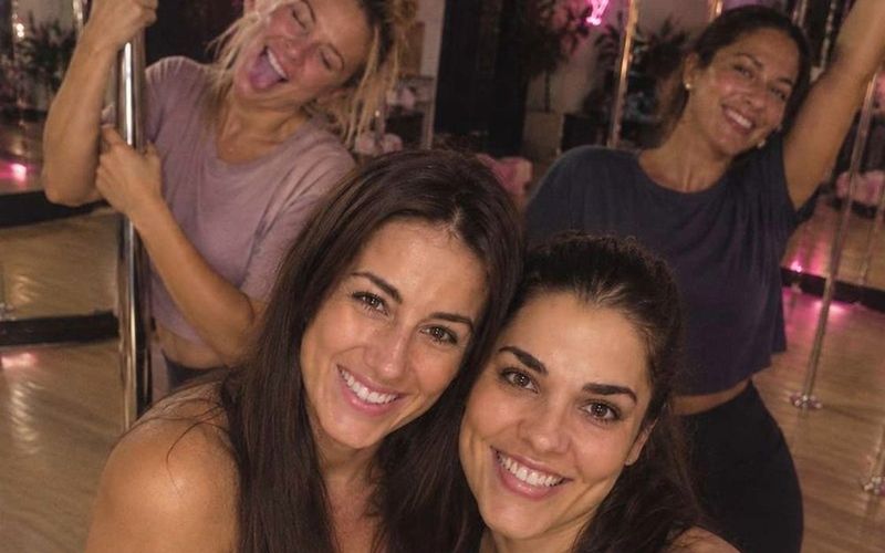 Friends grinning in a group selfie by the poles after their private pole dancing class on a Melbourne girls weekend