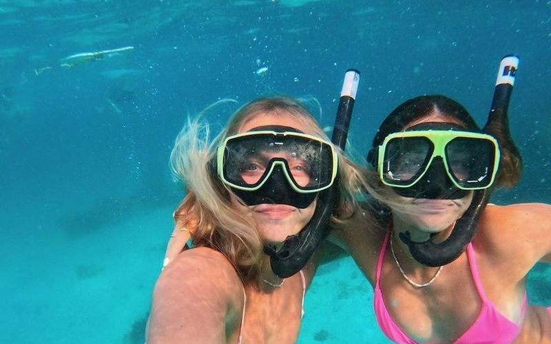 Two friends in snorkel masks grinning for an underwater selfie in clear water on a Brisbane girls trip