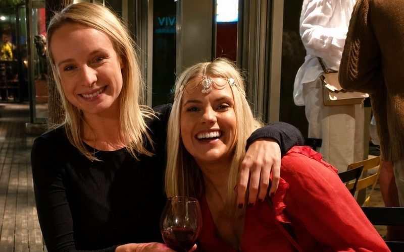 Two friends laughing together over a spread of tarot cards on a Brisbane girls weekend