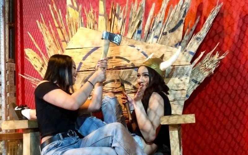 Two friends clowning around on a timber throne, one holding an axe on a Gold Coast girls trip