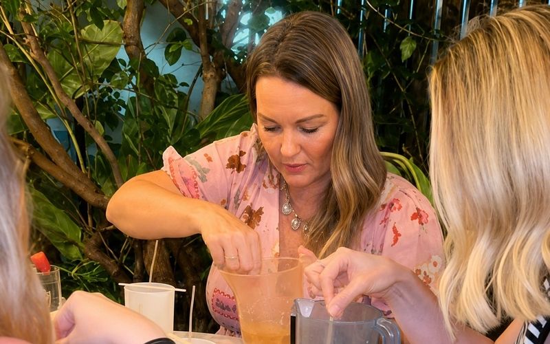 Friends pouring candle wax into jugs around a small table on a Gold Coast girls trip