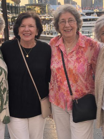 Four friends arm in arm on a harbour boardwalk at golden hour