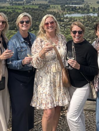 Five friends with white wine on a cellar door terrace above the vineyards