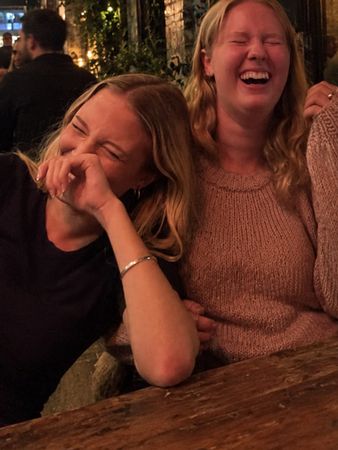 Two friends cracking up laughing at a bar table