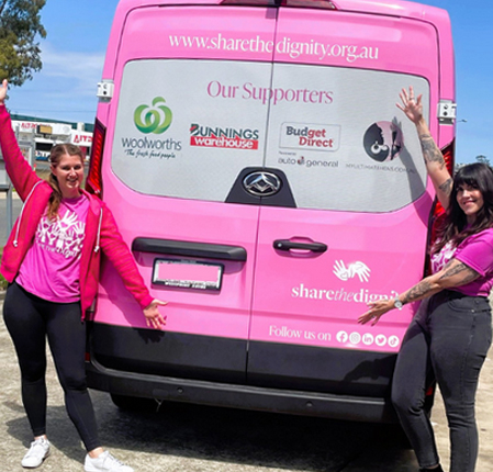 Two of the My Ultimate team in pink, standing either side of the Share the Dignity van