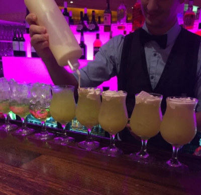 Photo sent in with this review: A bartender pouring a row of frozen cocktails under pink bar lights