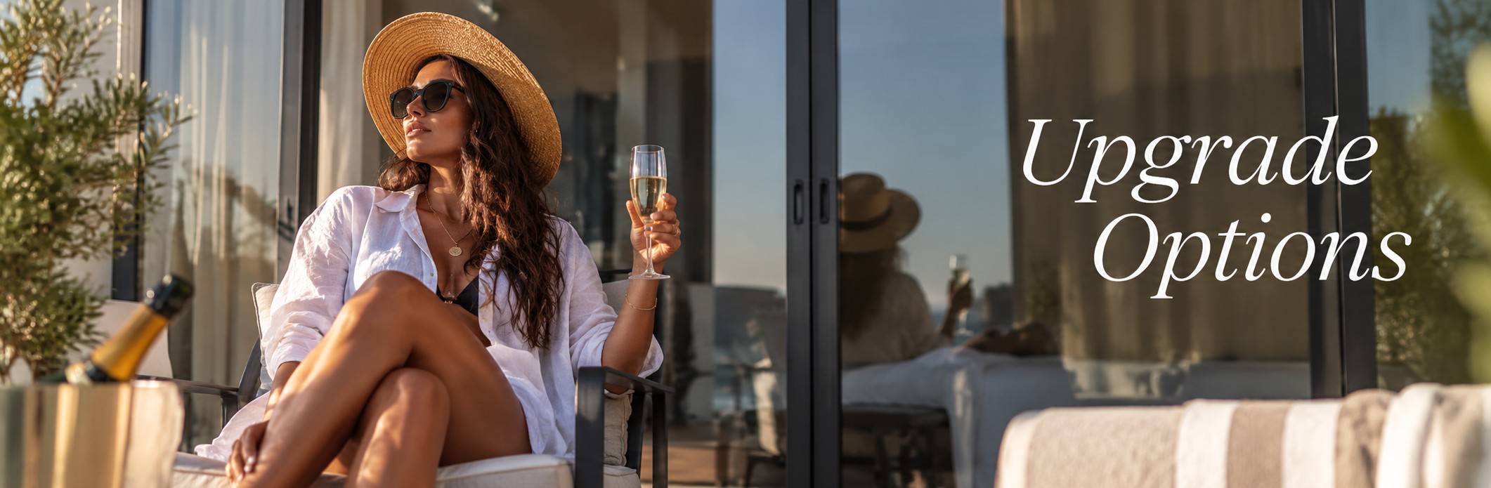 Woman in a sun hat and sunglasses holding a glass of bubbles on a sunny apartment balcony, with the words Upgrade Options