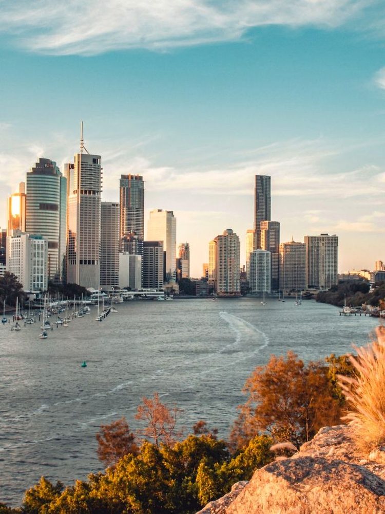 A city skyline and river at golden hour, boats moored below