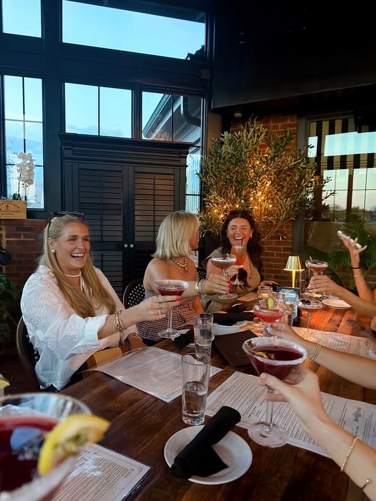 Friends toasting with cocktails around a dinner table