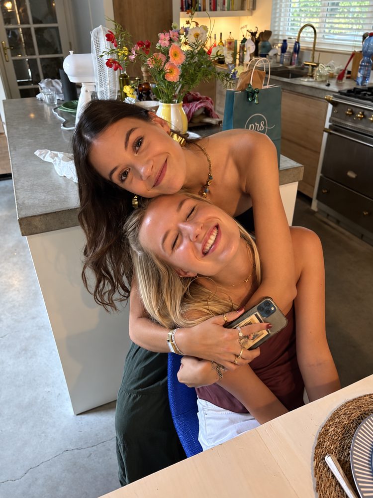 Two best friends hugging and smiling in a kitchen