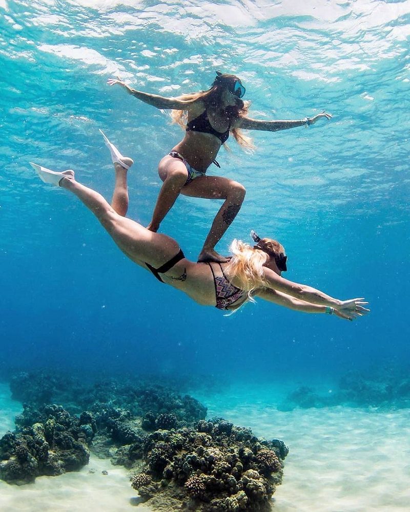 Two friends snorkelling over a coral reef in clear blue water
