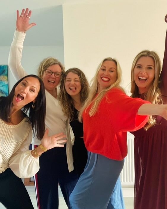 Five friends posing and laughing together at home on a girls weekend