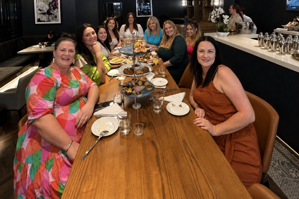 The girls around a long table set with high tea stands