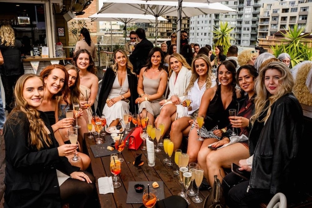 A big group of friends toasting drinks at a rooftop table