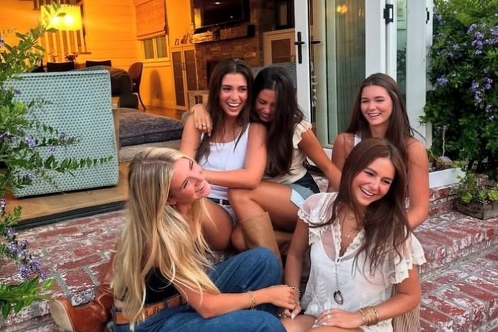 Four friends laughing together on the steps of the apartment