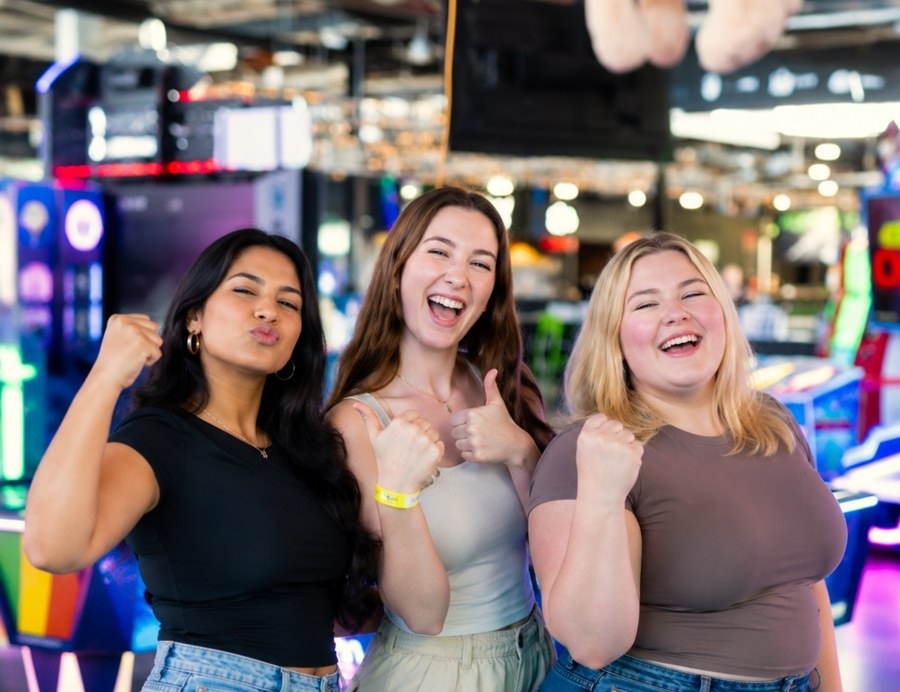 Three friends fist pumping and grinning at an indoor activity park