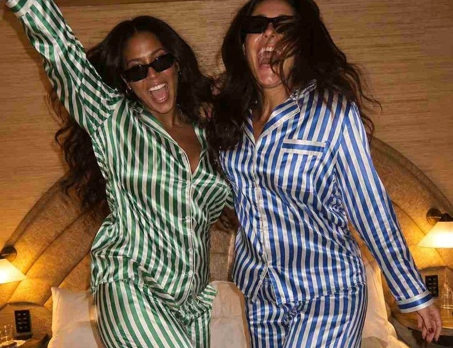 Two friends in striped pyjamas dancing and laughing in the apartment