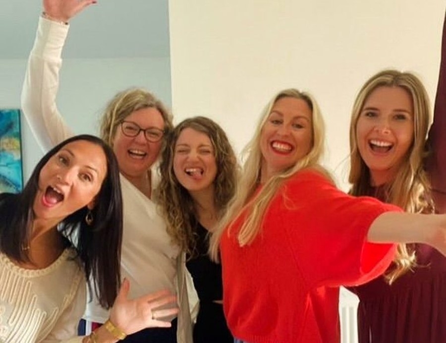 Five friends laughing in a group selfie at the apartment