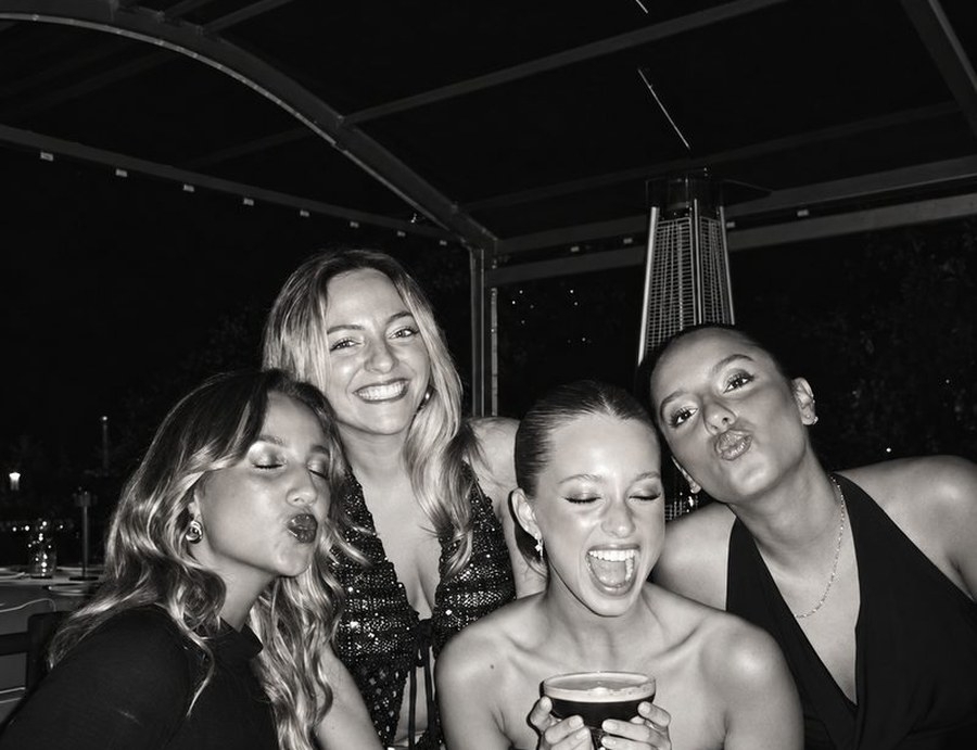 Black and white shot of four friends laughing on a rooftop at night
