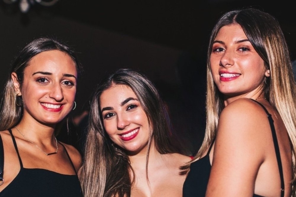 Three friends smiling together on a night out in the city