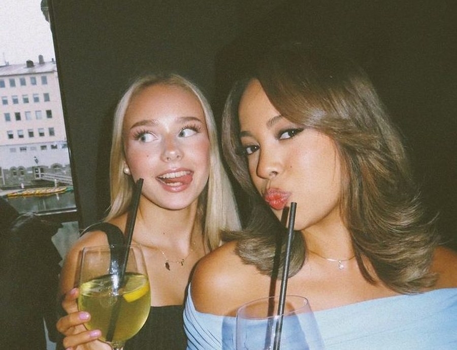 Two friends sipping drinks through straws on a night out