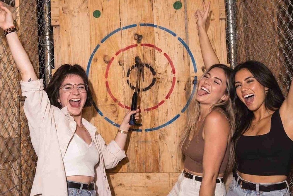 Three friends cheering beside the bullseye at axe throwing