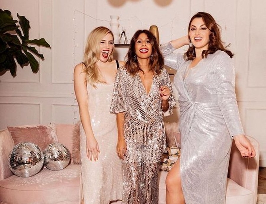 Three friends in sequins laughing while getting ready in the apartment