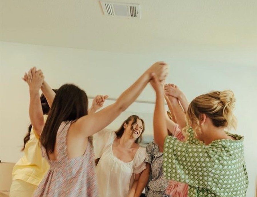 Friends dancing with their hands joined in the air in the apartment