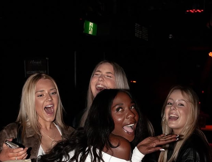 Friends laughing together in a dark, moody booth on a night out