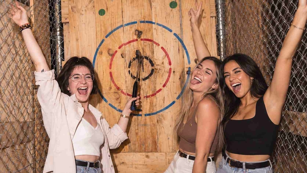 Three friends celebrating a bullseye together at an axe throwing session