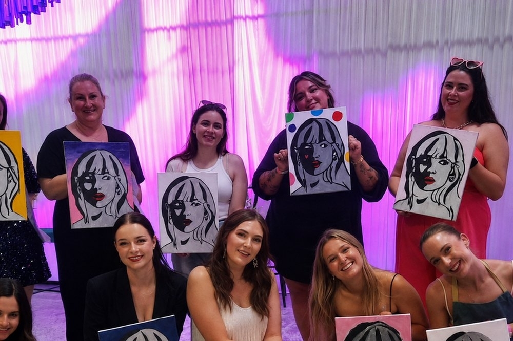 Friends holding up the pop art portraits they painted at a workshop