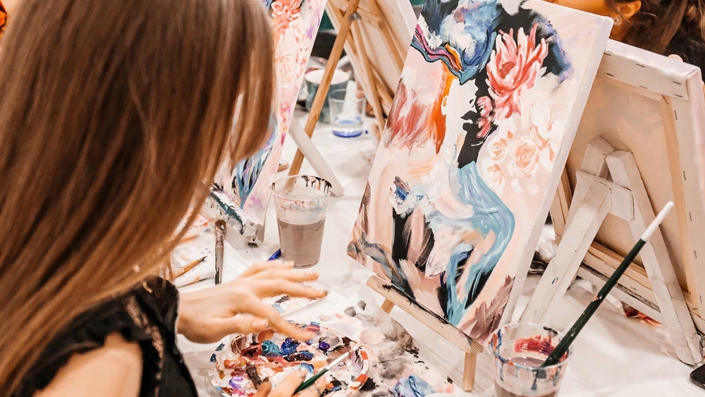 A friend adding colour to her canvas in the middle of a painting workshop