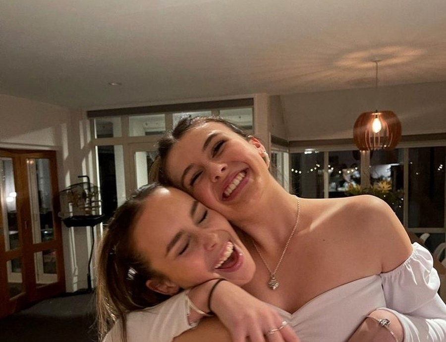 Two friends cheek to cheek and laughing in the apartment living room