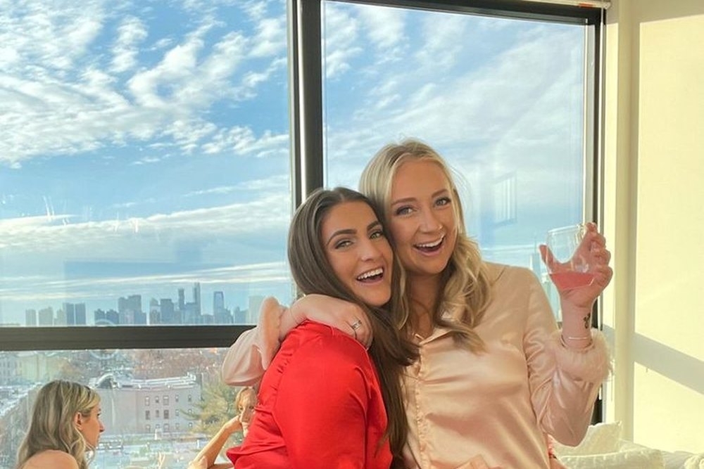 Friends in satin pyjamas hugging in a sunny city view apartment