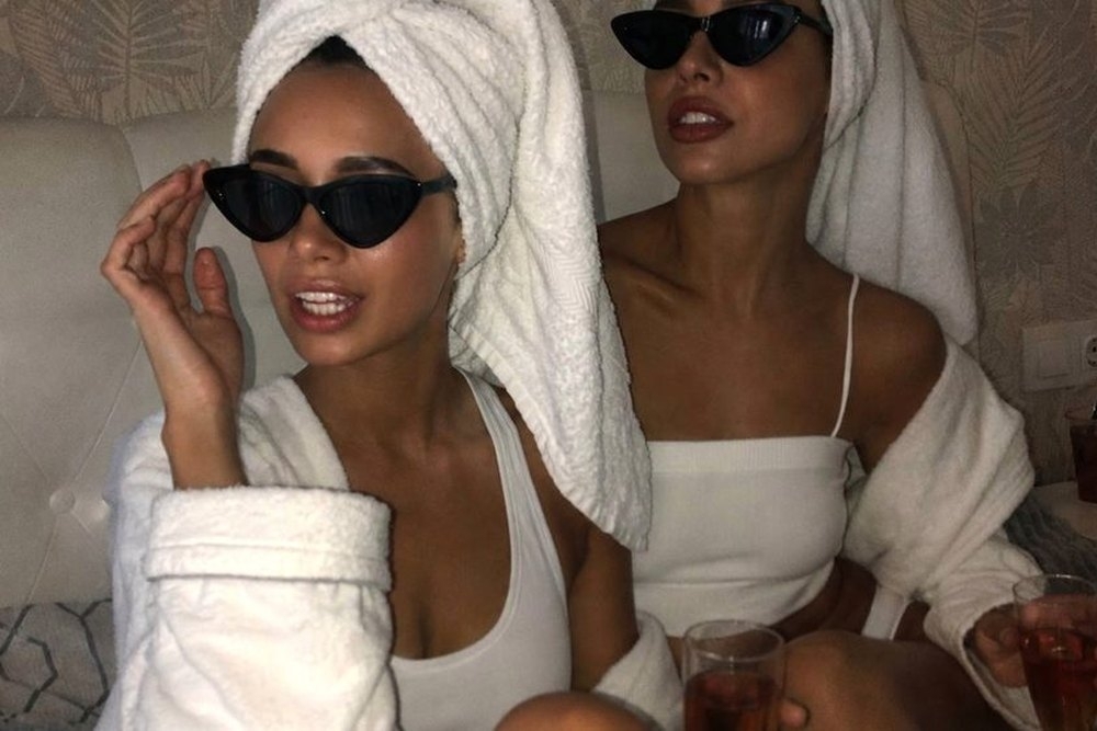 Two friends in towel turbans and sunglasses with drinks while getting ready