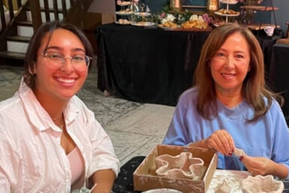 Two friends smiling over their clay at a pottery workshop