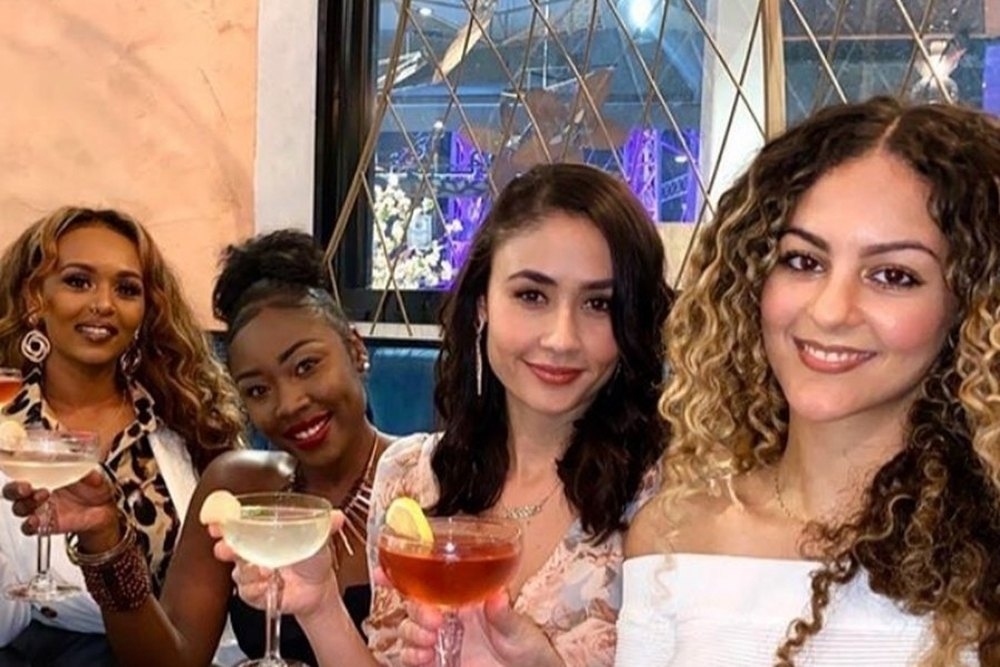 Four friends smiling with drinks at their table on a night out