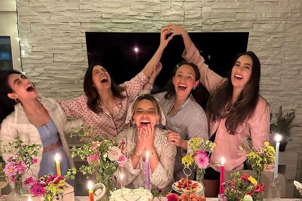 The girls in pyjamas cheering behind a candlelit spread back at the apartment